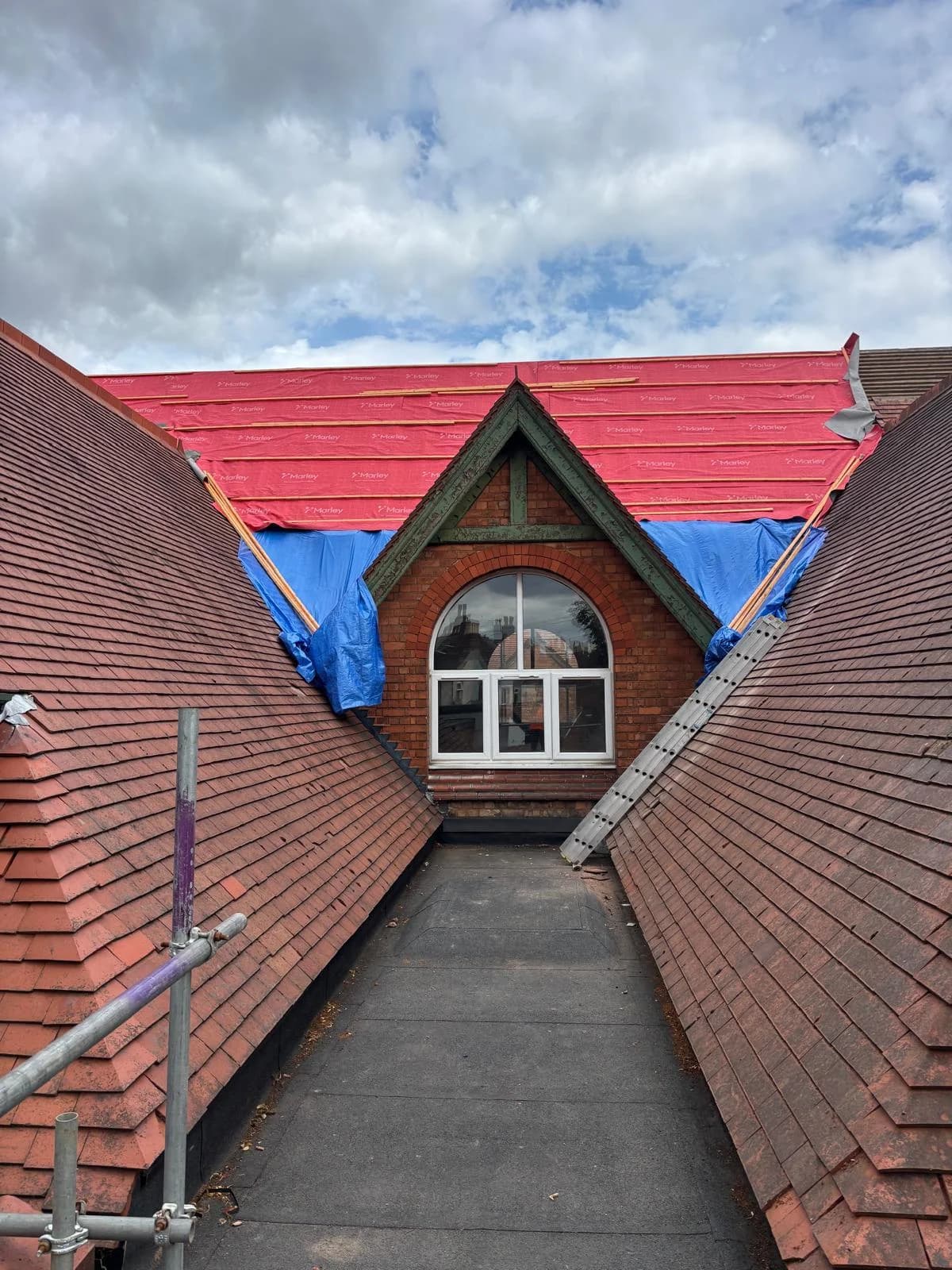 Red tile gable roof with new ridge and scaffolding access