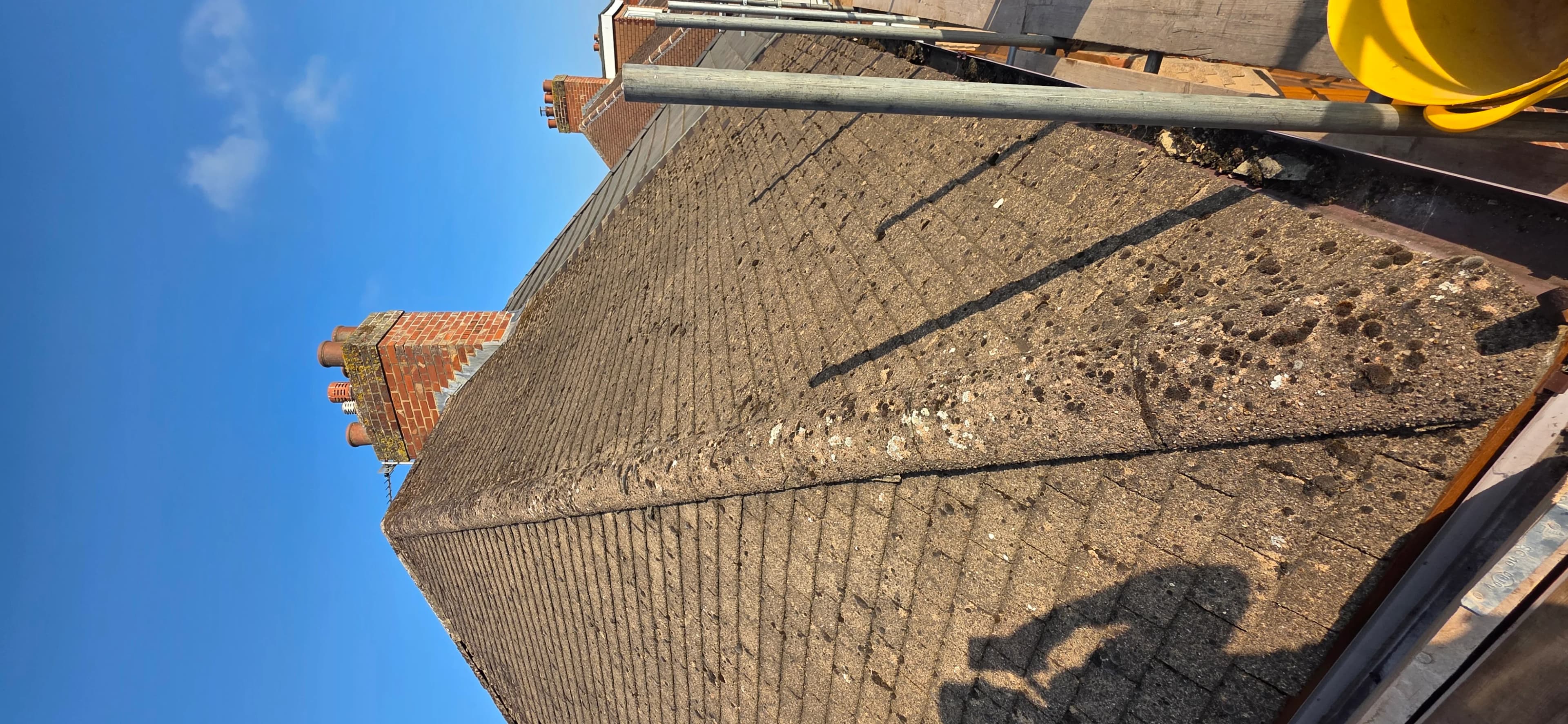 Looking up a roof edge and scaffolding against blue sky