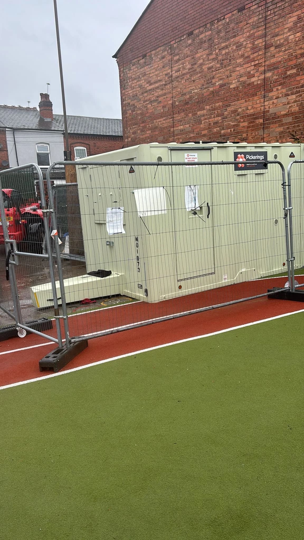 Site welfare cabins beside a running track during roof works