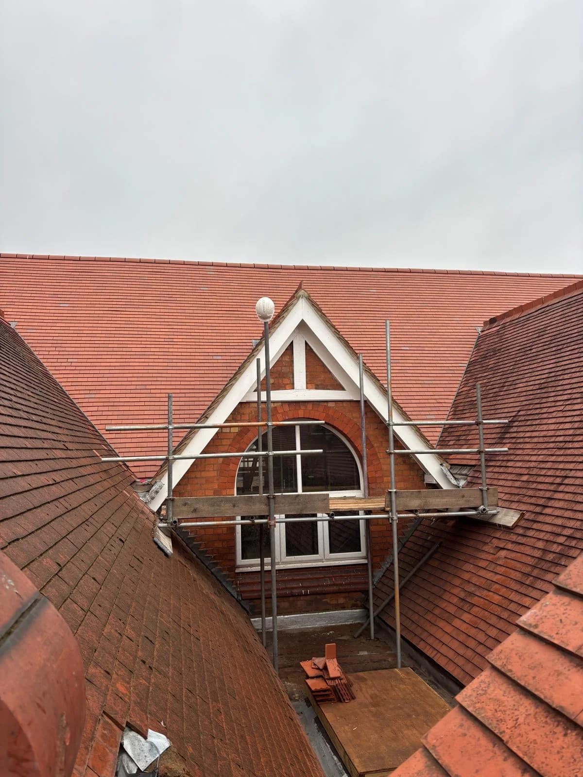 Red tile gable roof with attic window and scaffolding